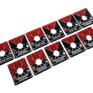 May include: A set of square game tokens with a red and black geometric design. Each token features a central hole and printed text, including "Baktoid Drone," "Colicoid Interceptor," and "Separatist Predator."