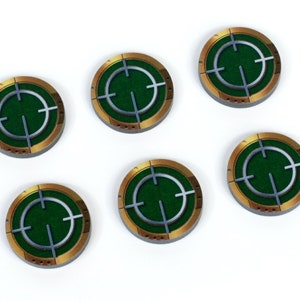 May include: Six green and gold target tokens with a silver crosshair in the centre. The tokens are circular and have a raised edge.