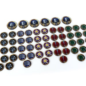 May include: A selection of circular game tokens with diverse designs. Some tokens display letters A to F, while others feature symbols such as stars, arrows, and targets. The tokens are in shades of blue, gold, red, and green.