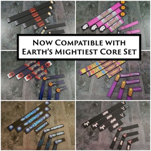 Può includere: Un set di buste per carte colorate con vari nomi di supereroi stampati su di esse. Le buste sono compatibili con il set base di Earth's Mightiest. Il testo "NOW COMPATIBLE WITH EARTH'S MIGHTIEST CORE SET" è stampato in bianco su sfondo nero.