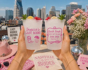 May include: Two clear plastic cups filled with ice, lemon slices, raspberries, and mint sprigs. The left cup features pink text reading Jessica's LAST RODEO with a boot and disco ball. The right cup features pink text reading Bach Bash, Let's Get Rowdy!, JUNE 2030, Nashville, TN.