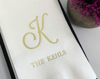 May include: White paper napkin with a gold cursive letter K and the text "THE KEHLS" in gold lettering.