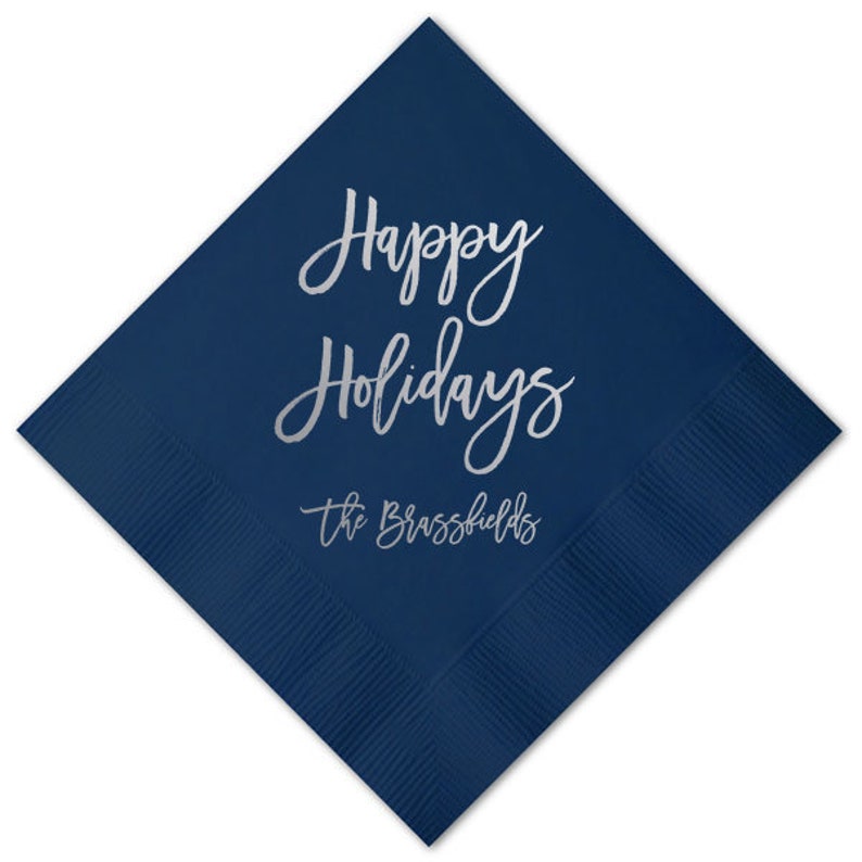 May include: Navy blue paper napkins with silver foil lettering that reads "Happy Holidays" and "The Brassfields".