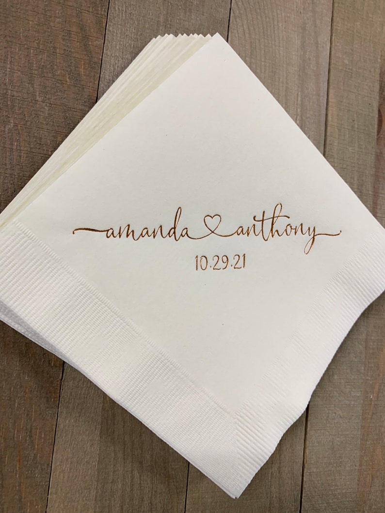 May include: White paper napkins with the text "amanda &hearts; anthony" and the date "10.29.21" printed in brown ink.