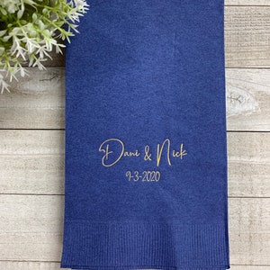 May include: A navy blue paper napkin with gold lettering that reads "Dani & Nick 9-3-2020".