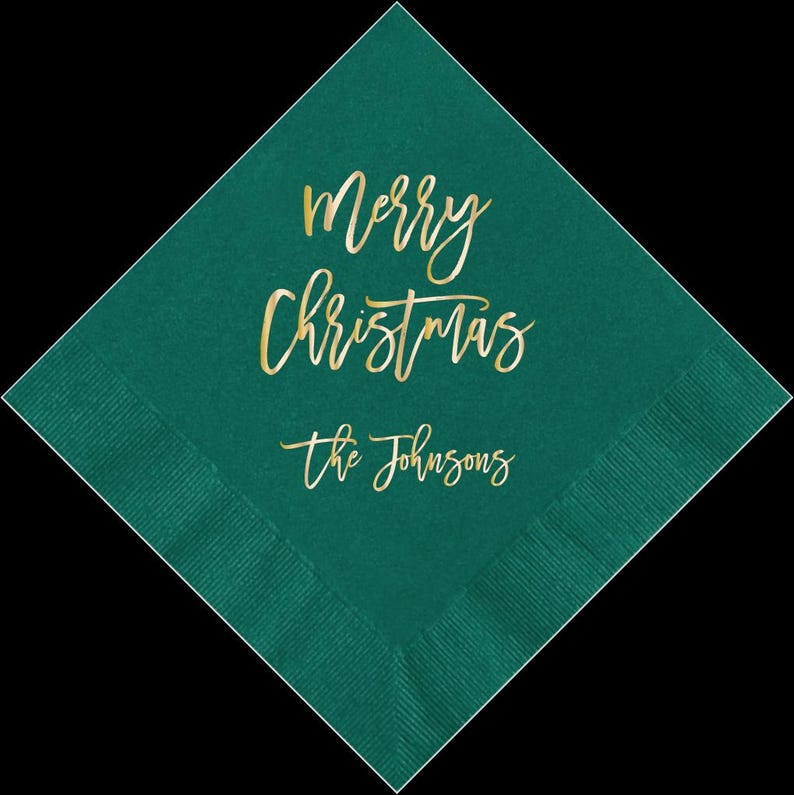 May include: Teal green paper napkin with gold foil lettering that says "Merry Christmas" and "The Johnsons".
