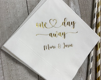 May include: White paper napkins with gold foil lettering that reads "one day away" with a heart symbol and "Mimi & Jason".
