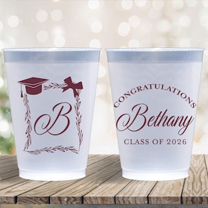 May include: Two white plastic cups with a light blue rim. One cup features a graduation cap and the letter "B" in a decorative frame. The other cup says "Congratulations Bethany Class of 2026" in burgundy.