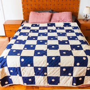 May include: A white and blue checkered quilt with white polka dots on a wooden bed frame. The quilt is made of cotton fabric and has a vintage look.