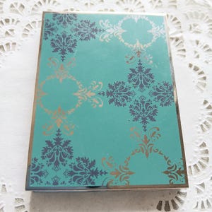 May include: A teal blue card with a gold and black damask pattern.