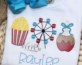 May include: White embroidered t-shirt with a red and white striped popcorn bucket, a blue and red Ferris wheel, and a red and brown caramel apple. The text "A Southern Stitch" and the name "Raylee" are embroidered in blue thread.