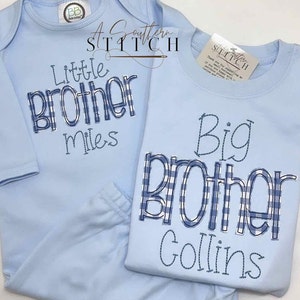 May include: Two light blue baby onesies with embroidered text. One onesie says "Little Brother Miles" and the other says "Big Brother Collins" with a blue and white checked pattern.