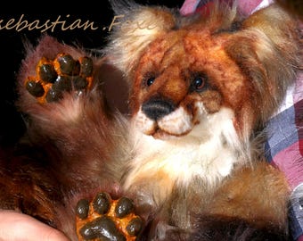 Puede incluir: Un cachorro de león de peluche con pelaje marrón y canela, un pecho blanco y ojos oscuros. El cachorro de león tiene patas de color marrón anaranjado con almohadillas negras. La imagen incluye el texto "@sebastian.Foxe".