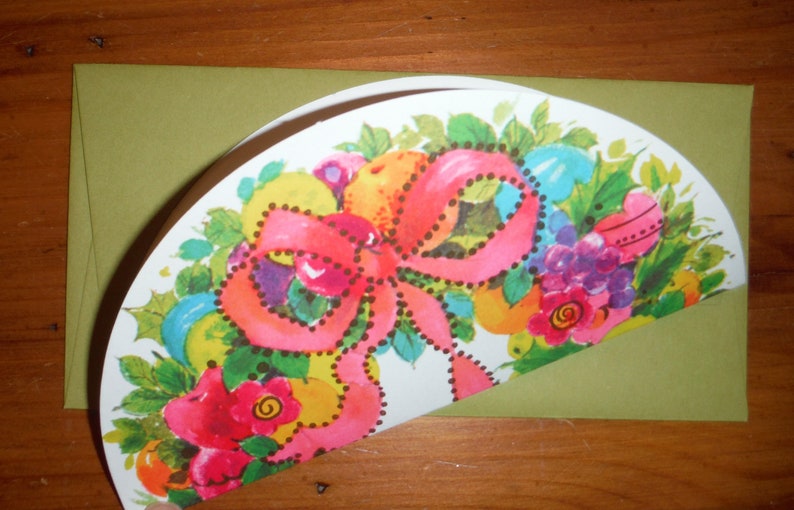 Peut inclure: Une carte verte avec un motif floral color&eacute; comprenant un n&oelig;ud rose, des feuilles vertes et des fleurs rouges, jaunes et bleues. La carte est pli&eacute;e en deux et le motif est sur le devant.