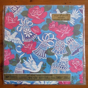 May include: A blue and white gift wrap with pink roses and white doves. The paper is designed for showers and weddings. The text on the paper reads "Rust & Craft Shower Wedding/Marriage 60 2 Sheets Each Sheet 19 3/4" x 29" 50.1 x 73.6 cm Total 7.95 sq ft .737 m&sup2; Rust Craft Ltd. Scarborough, Ontario, M1P 3C4"
