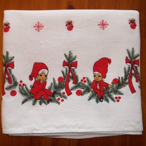 May include: White Christmas tablecloth with a repeating border of green fir branches, red bows, and red baubles. The border includes illustrations of elves in red outfits and hats. Red snowflakes and baubles are also printed on the top.