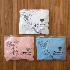 May include: Three clear plastic zippered pouches with a girl swinging on a swing design. The pouches are pink, white, and blue. Each pouch has the text "Diamond Tricot Stockings" and a diamond graphic.