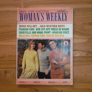 May include: Vintage Woman's Weekly magazine cover featuring three people in knitwear. The cover has text that reads "Best for Knitting" and "Super Pull-Out... Cold-Weather Knits". The magazine is on a wooden surface.