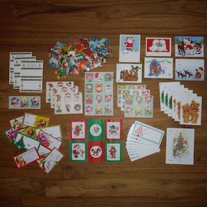 Op de afbeelding: Een verzameling kerst-thema briefpapier en stickers, waaronder cadeaulabels, adreslabels en decoratieve stickers. De ontwerpen bevatten de kerstman, sneeuwpoppen, rendieren en andere feestelijke afbeeldingen in diverse kleuren.