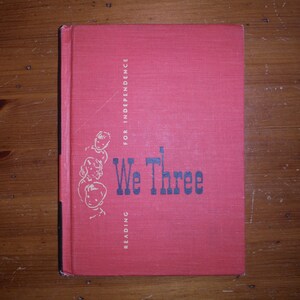May include: A red book with the title "We Three" and the words "Reading for Independence" on the cover. The cover features a black and white illustration of three children.
