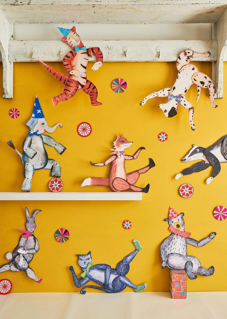Puede incluir: Una exhibici&oacute;n caprichosa de recortes de animales de papel, incluyendo un tigre, un elefante, un zorro y un oso, contra un fondo amarillo. Cada animal est&aacute; adornado con sombreros de fiesta y accesorios. Decoraciones coloridas de estrellas salpicadas.