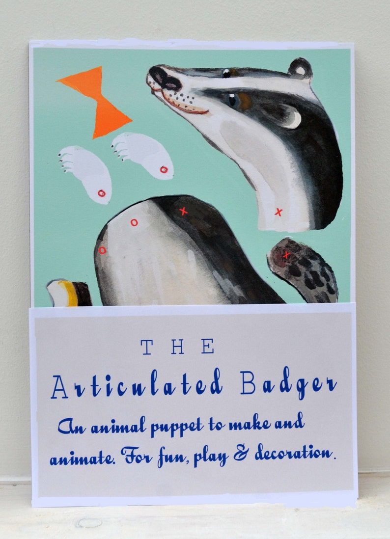 Puede incluir: Ilustraci&oacute;n de una marioneta de tej&oacute;n articulada, con partes separadas sobre un fondo verde agua. El texto "THE Articulated Badger" se muestra debajo, con la leyenda "An animal puppet to make and animate. For fun, play & decoration."