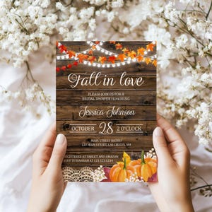May include: A bridal shower invitation with a rustic wooden background. The text "Fall in love" is displayed, along with the name "Jessica Johnson" and the date "October 28". The invitation features fall-themed decorations, including pumpkins and autumn leaves.