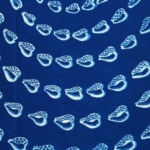 Può includere: Primo piano di un tessuto con un motivo ripetuto di conchiglie bianche su sfondo blu scuro. Le conchiglie sono dettagliate con texture a puntini e linee curve, creando un tema nautico.