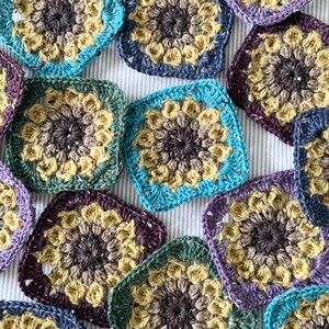 May include: A collection of colourful crocheted squares with a variety of patterns and colours, including purple, blue, green, and brown.