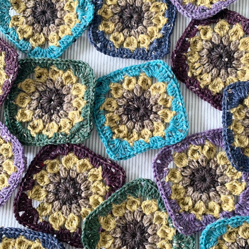 May include: A collection of colourful crocheted squares with a variety of patterns and colours, including purple, blue, green, and brown.