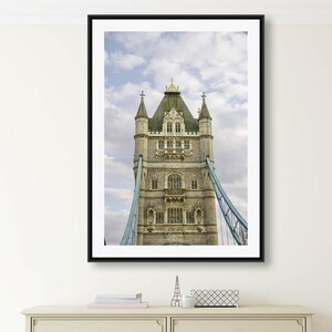 May include: A black framed photograph of the Tower Bridge in London, England. The photo shows the top portion of the bridge, including the towers and the suspension cables.