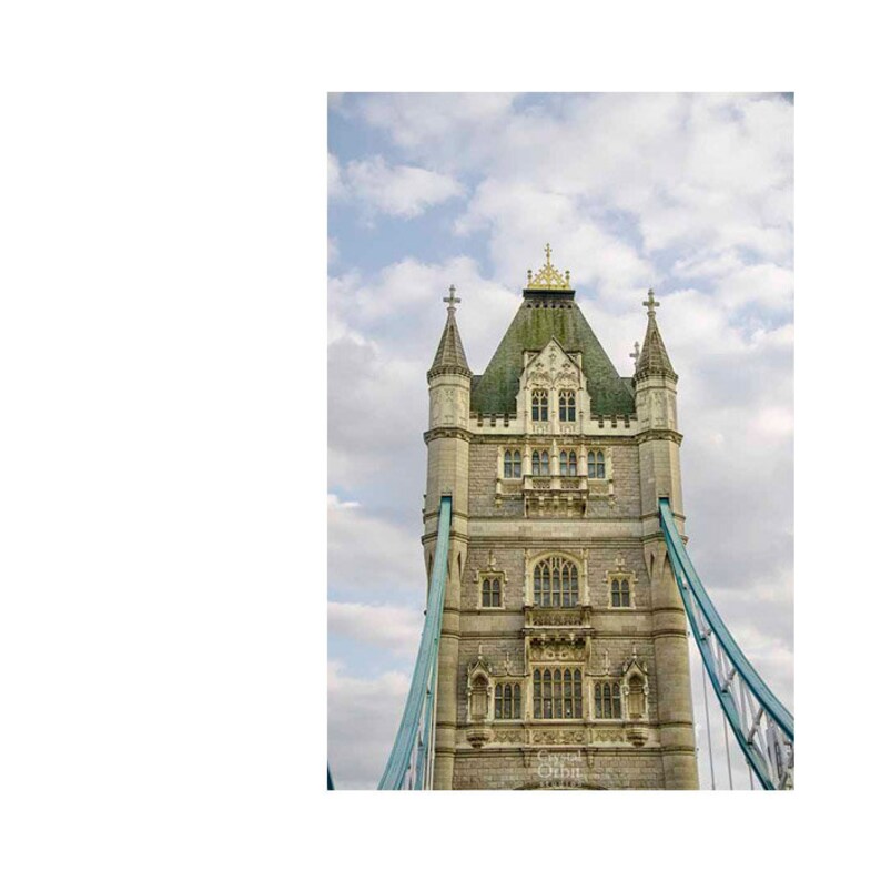 May include: A close-up view of the top of Tower Bridge in London, England. The bridge is made of stone and has a distinctive architectural style. The bridge is adorned with decorative details, including a pointed roof and a cross at the top.
