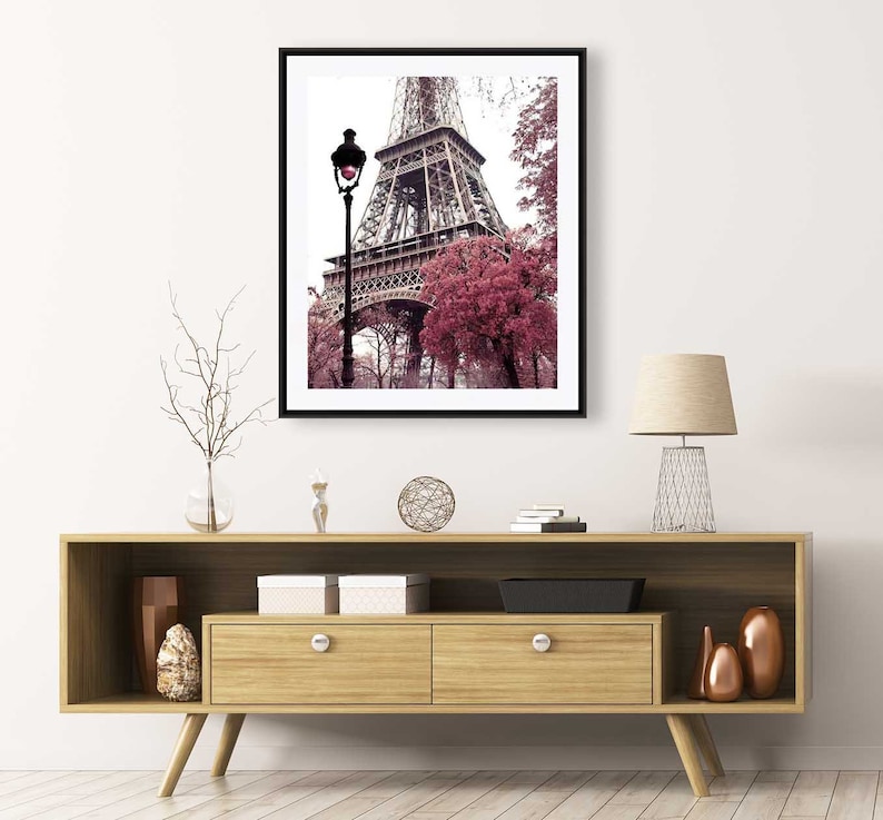 May include: A framed photograph of the Eiffel Tower in Paris, France. The tower is surrounded by trees with pink leaves. A street lamp is in the foreground.