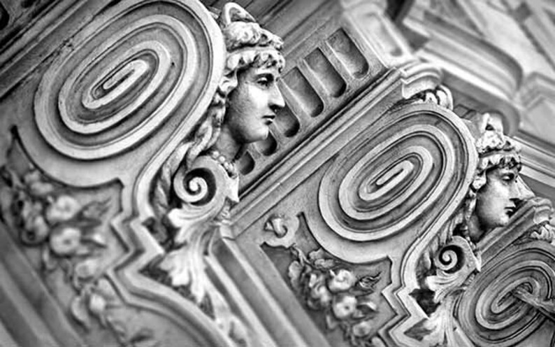May include: Black and white photograph of a detailed, ornate, architectural design with a spiral pattern. The design features a sculpted human face with a crown.