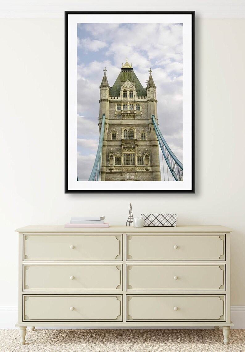 May include: A black framed photograph of the Tower Bridge in London, England. The photo shows the top portion of the bridge, including the towers and the suspension cables.