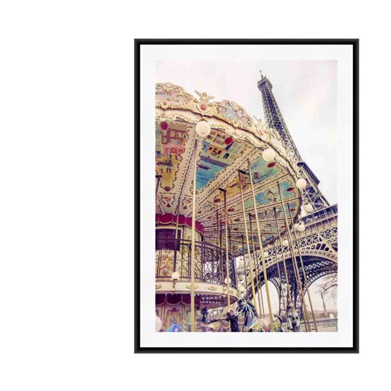 May include: A vintage carousel with a colorful painted roof and ornate details stands in front of the Eiffel Tower in Paris, France. The carousel is lit with white lights and has a black metal railing. The Eiffel Tower is in the background, with its intricate metal structure visible.