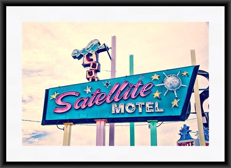 May include: A vintage neon sign for a motel called "Satellite Motel". The sign is blue with pink lettering and features a stylized satellite with stars around it.