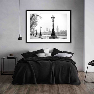May include: Black and white photograph of the Houses of Parliament in London, England. The photo is framed and hanging on a wall above a black bed with white pillows.