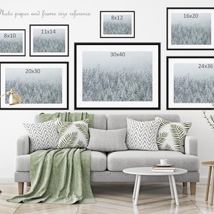 May include: A white wall with a couch and two end tables. There are eight framed pictures of a snowy forest scene hanging on the wall. The pictures are labeled with their dimensions in inches, such as 8x10, 11x14, 20x30, 30x40, 24x36, 8x12, and 16x20.