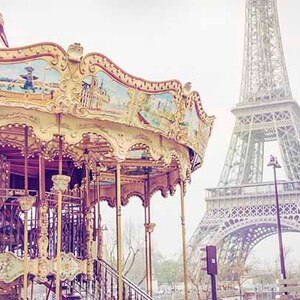Op de afbeelding: Een vintage carrousel met sierlijke details staat voor de Eiffeltoren in Parijs, Frankrijk. De carrousel is geschilderd in pastelkleuren en heeft een gouden rand. De Eiffeltoren is een metalen constructie met een lichtgrijze afwerking.