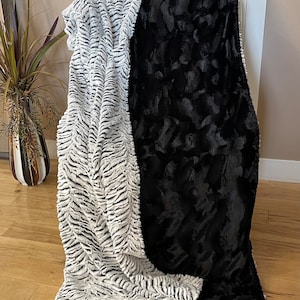 May include: A soft, plush throw blanket with a black side and a white and gray zebra print side.