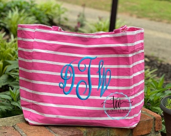May include: Pink and white striped tote bag with a blue monogram "DTL" embroidered on the front. The bag has a white label with the text "The Crafty Virgo" on the bottom.