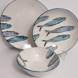 Könnte beinhalten: Ein Set aus drei Keramiktellern mit einem blauen und weißen Fischdesign. Die Teller sind ein Speiseteller, ein Salatteller und eine Schüssel.
