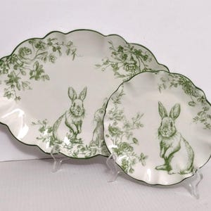 May include: Two-piece serving set featuring a large, scalloped-edge platter and a smaller plate. Both are white with a green floral and bunny design. The edges are trimmed in green, creating a cohesive Easter-themed aesthetic.