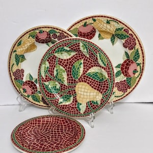 May include: A set of decorative ceramic plates with fruit designs. The plates feature a mosaic-style pattern with pears, apples, and berries in shades of red, green, and yellow. The set includes plates of various sizes, perfect for serving or display.