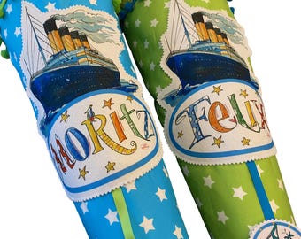 May include: Two colorful school cones, one blue and one green, decorated with star patterns and a ship illustration. The blue cone has the name "Moritz" and the green cone has the name "Felix". Both cones have the text "1. Klass".