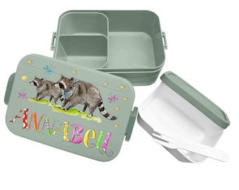 May include: A sage green bento box with three internal compartments and a matching lid. The lid features a watercolor illustration of two raccoons, butterflies, and stars, with the name ANNABELL written in colorful, patterned block letters.
