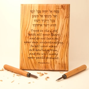 Op de afbeelding: Een houten plaquette met een Hebreeuwse inscriptie en een Engelse vertaling van het vers Spreuken 3:5,6. De plaquette is gemaakt van olijfhout en heeft een natuurlijke houtnerf. De inscriptie luidt: "Vertrouw op de Heer met heel je hart en vertrouw niet op je eigen verstand. Ken Hem op al je wegen, en Hij zal je paden recht maken."