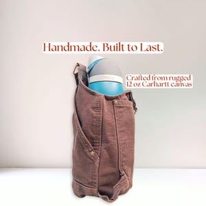 Close side view of rugged canvas bottle holder highlighting durable construction and structured shape while holding a large bottle.