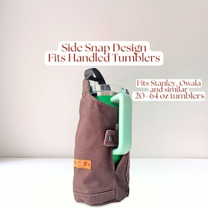 Water bottle holder with side snap strap securing a handled tumbler, demonstrating compatibility with large handled cups like Stanley tumblers.